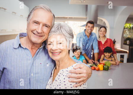 Porträt von älteres Paar mit Familie, die Zubereitung von Speisen im Hintergrund Stockfoto