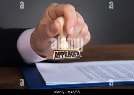 Nahaufnahme von einer Person Hand Stempeln auf genehmigte Dokument Stockfoto