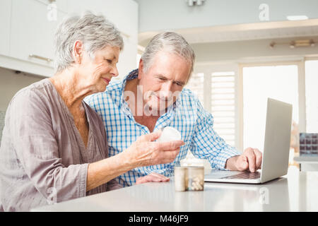 Ältere Frau zeigt Pillen, Mann mit laptop Stockfoto