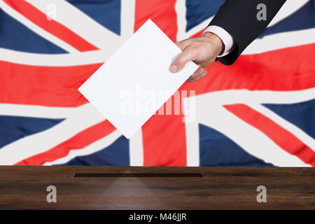 Unternehmer Hand Abstimmung in die Wahlurne Vor Großbritannien Flagge Stockfoto