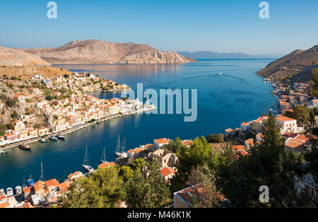 Panorama Aussicht über das Dorf und den Hafen Gialos auf der griechischen Insel Symi und die unbewohnte Inselchen Nimos, Dodekanes, Griechenland und die Türkei im Hintergrund Stockfoto