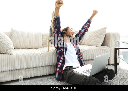 Happy Guy frohlockt mit seinem Hund sitzt in der Nähe der Couch im Wohnzimmer. Stockfoto