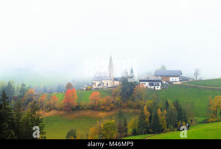 Kirche von Santa Magdalena im Herbst Nebel. Funes Tal, Südtirol, Dolomiten, Italien Stockfoto