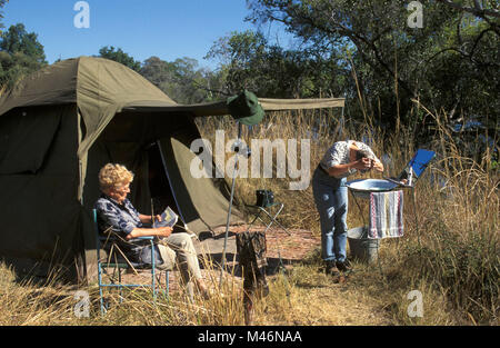 Simbabwe. In der Nähe von Victoria Falls. Zambezi River. Tourist. Camping. Frau vor Zelt Lesen und Waschen. Stockfoto