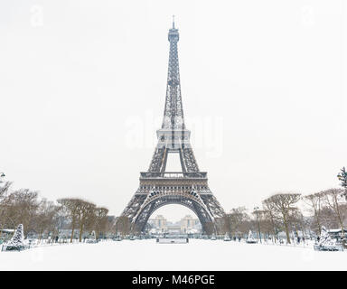 Der Eiffelturm an einem Wintertag in Paris von der Champ de Mars mit einem schneebedeckten Rasen im Vordergrund gesehen. Stockfoto