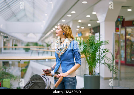 Junge Frau mit Baby während des Einkaufs Stockfoto