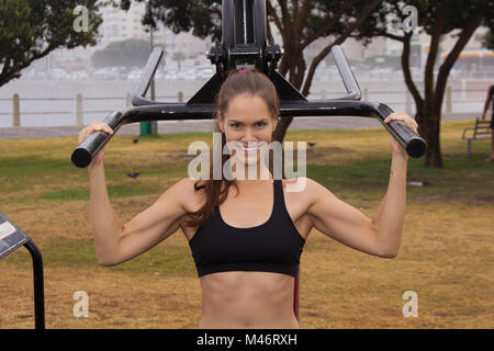 Ein fit Frauen im Sport Kleidung mit einem Fitnessbereich im Freien und lächelnd in die Kamera Stockfoto