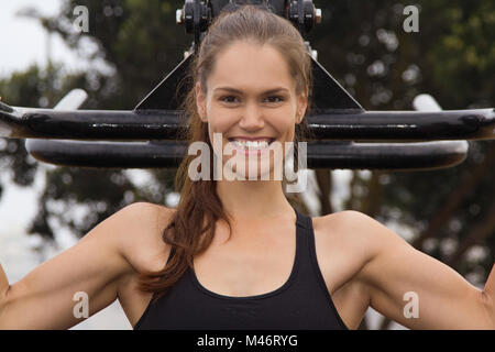 Ein fit Frauen im Sport Kleidung mit einem Fitnessbereich im Freien und lächelnd in die Kamera Stockfoto