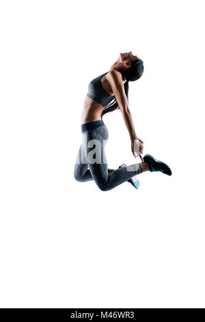 Vertikale Seite Profil anzeigen Foto der schönen Sportlich fit schlanke Frau, springen und versuchen, ihre Fersen zu berühren, sie ist in Beschlag nehmen Sie sich zurück und suchen, Stockfoto
