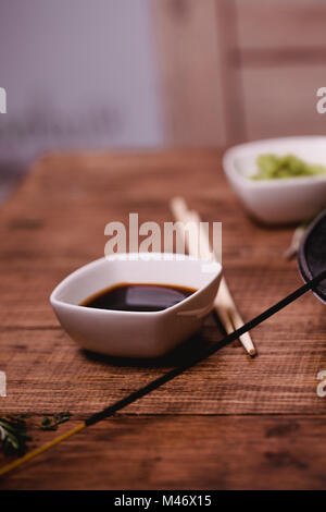 Closeup Sojasauce, Stöcke, Wasabi und für Sushi auf braune Holztisch Hintergrund. Ansicht von oben. Stockfoto