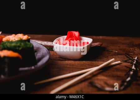 Closeup eingelegter Ingwer, Sticks, Wasabi und Sojasauce für Sushi auf braune Holztisch Hintergrund. Ansicht von oben. Stockfoto