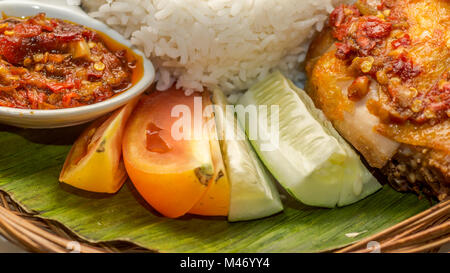 Indonesien kulinarisches Menü. Reis, gebratenes Huhn, Chili Sauce, Tomaten und Gurkenscheiben Stockfoto