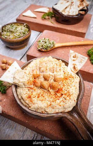 Hummus serviert mit frischem Fladenbrot und sprießen, gewürzt mit Paprika in vintage Keramikplatte Stockfoto