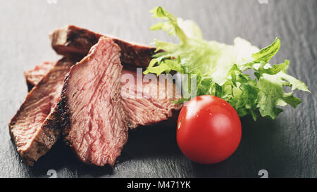 Entrecote-Beefsteak in Scheiben geschnitten auf Schiefer Brett mit Gemüse Stockfoto