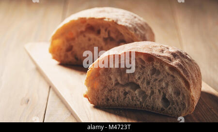 Hälften des frischen Ciabatta auf Oliven Schneidebrett Stockfoto