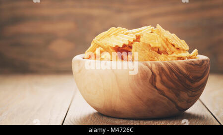 geriffelte Kartoffelchips mit Paprika-Geschmack in Holzschale Stockfoto