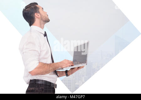 Zusammengesetztes Bild von anspruchsvollen Geschäftsmann stehend mit einem Laptop Stockfoto