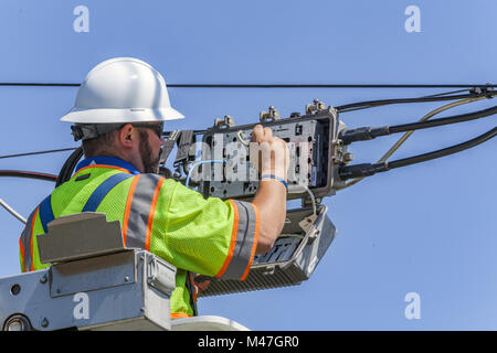 Als Linienrichter für ein großes Kabel USA Service Unternehmen tests Signalstärke kabel Leitungen während der Arbeit an einer erhöhten Arbeitsbühne. Stockfoto