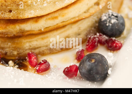 Frühstück Pfannkuchen mit Heidelbeeren, Granatapfel Samen und Ahornsirup auf weißem Hintergrund mit sehr geringer Tiefenschärfe isoliert. Nahaufnahme Stockfoto