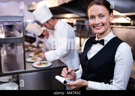 Lächelnd Kellnerin mit Notizblock in Großküchen Stockfoto