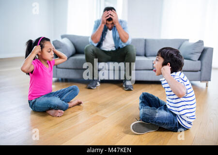 Verärgert Vater sitzt auf dem Sofa, während Kinder kämpfen Stockfoto