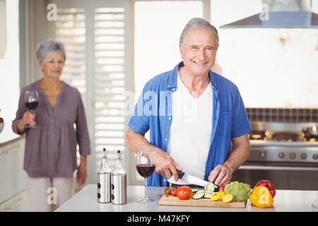 Porträt von senior woman Schneiden von Gemüse mit Frau im Hintergrund Stockfoto
