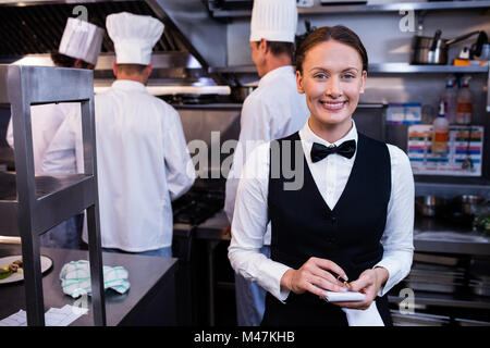 Lächelnd Kellnerin mit Notizblock in Großküchen Stockfoto