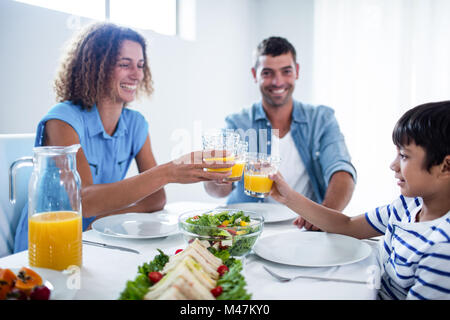 Familie Toasten Gläser Orangensaft beim Frühstück Stockfoto