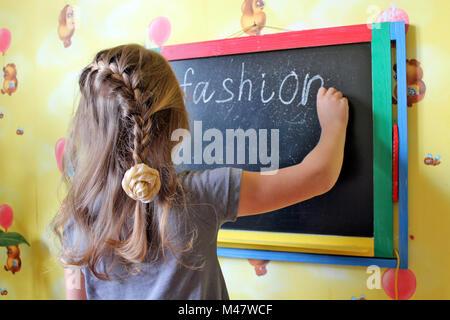 Mädchen mit Zöpfen schreibt Word Mode auf blackboard Stockfoto