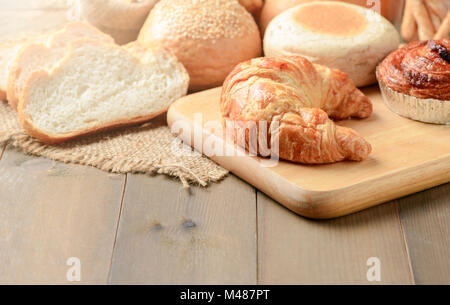 Hausgemachte Croissants und Brot auf alten Holz Hintergrund, frische Backwaren Stockfoto