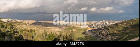 Großes Panorama der Stadt zwischen Hügeln mit niedrigen Gewitterwolken über dem Toten Meer Stockfoto