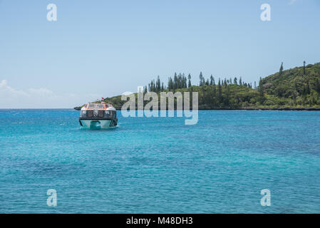 TADINE, Stute, NEUKALEDONIEN - Dezember 3, 2016: Ausschreibung Boot im türkisblauen Pazifik Wasser mit Kiefern, von Tadine Bucht in Mare, Neukaledonien Stockfoto