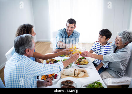 Familie Toasten Gläser Orangensaft beim Frühstück Stockfoto