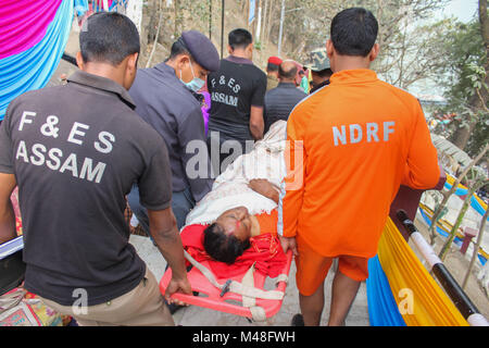 Guwahati, Indien. 14 Feb, 2018. NDRF (National Disaster Response Force) und SDRF (Staatliche Disaster Response Fund) Personal nahm eine verletzte ältere Frau für die Behandlung während der Shiva Puja zu Umananda Devaloi, ein Shiva Tempel auf der Pfaueninsel in der Mitte des Flusses Brahmaputra gelegen. Quelle: David Talukdar/Pacific Press/Alamy leben Nachrichten Stockfoto