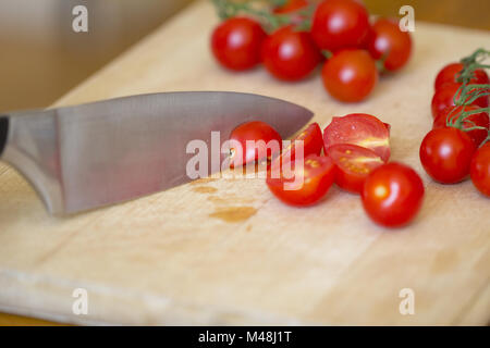 Kirsche Tomaten auf einem Schneidebrett aus Holz gehackt. Stockfoto