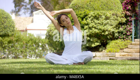 Wunderschöne junge Frau in weißen sitzen auf Rasen Stockfoto