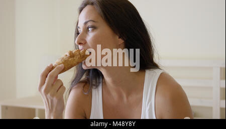 Frau frisch gebackenen Croissants im Bett Essen Stockfoto