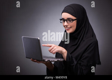 Die muslimische Frau im schwarzen Kleid vor einem dunklen Hintergrund Stockfoto