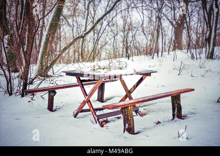 Holz- Tisch und Bank im Wald unter dem Schnee Stockfoto