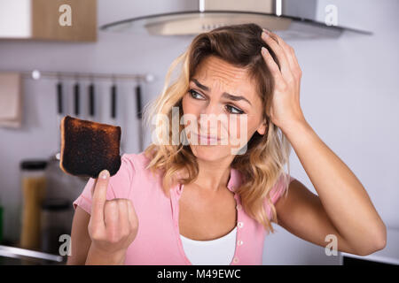 Nahaufnahme der Frustrierte junge Frau mit Toast in der Küche verbrannt Stockfoto