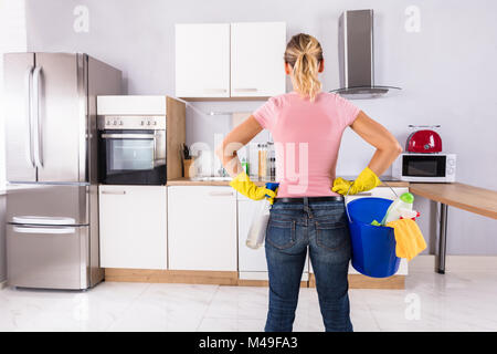Frau mit Handschuhen, die Reinigung von Ausrüstungen im Eimer stehen in der Küche Stockfoto