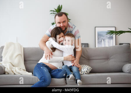 Foto der glücklichen Familie mit Sohn auf grau Sofa Stockfoto