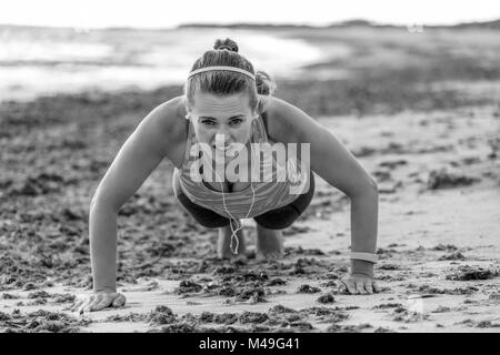 Erfrischende wilden Meer Seite Training. Junge passende Frau in Sports Gear, der am Ufer des Meeres pushups tun Stockfoto