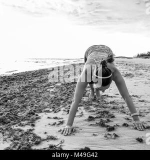 Erfrischende wilden Meer Seite Training. Junge aktive Frau in Sports Gear auf der Seeküste Stretching Stockfoto