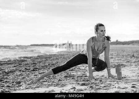 Erfrischende wilden Meer Seite Training. gesund fit Frau in Sports Gear auf der Seeküste Stretching Stockfoto