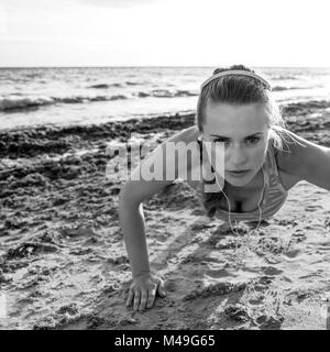 Erfrischende wilden Meer Seite Training. Aktiv fitness Frau in Sportswear am Strand Liegestütze machen Stockfoto