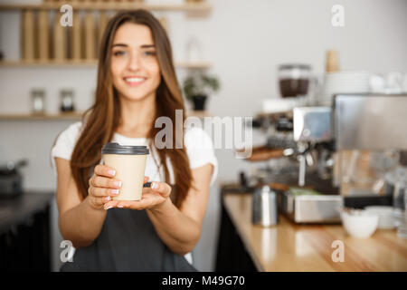 Kaffee Geschäftskonzept - Schöne kaukasischen Dame lächelte Kamera bietet Einweg entfernt heißen Kaffee in der modernen Coffee Shop nehmen Stockfoto