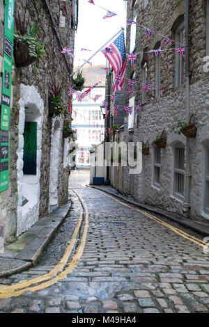 Straße mit Kopfsteinpflaster in der Barbican Bereich der Plymouth mit britischen und amerikanischen Flaggen fliegen, hinunter zum Hafen, mit einem gelben Linien Stockfoto