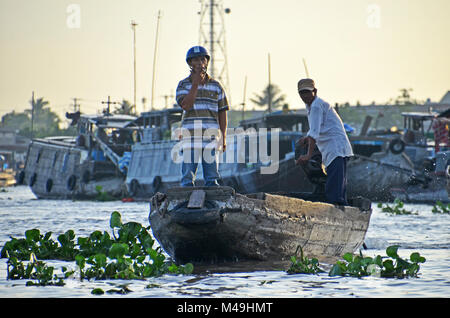 Ein Mann raucht eine Zigarette, während in der Bug eines Schiffes in Cai Rang Floating Market stehend, Can Tho, Vietnam Stockfoto