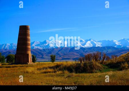 Burana Turm in Kirgisistan vor schneebedeckten Bergen. Teil der antiken Stadt Balasagun im 9. Jahrhundert gebaut Stockfoto